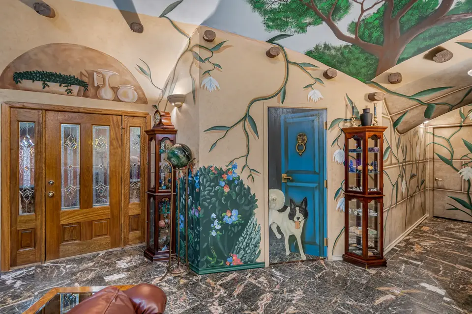 The front door, a hallway, and the door to the pantry feature whimsical murals. The front door, a hallway, and the door to the pantry feature whimsical murals.