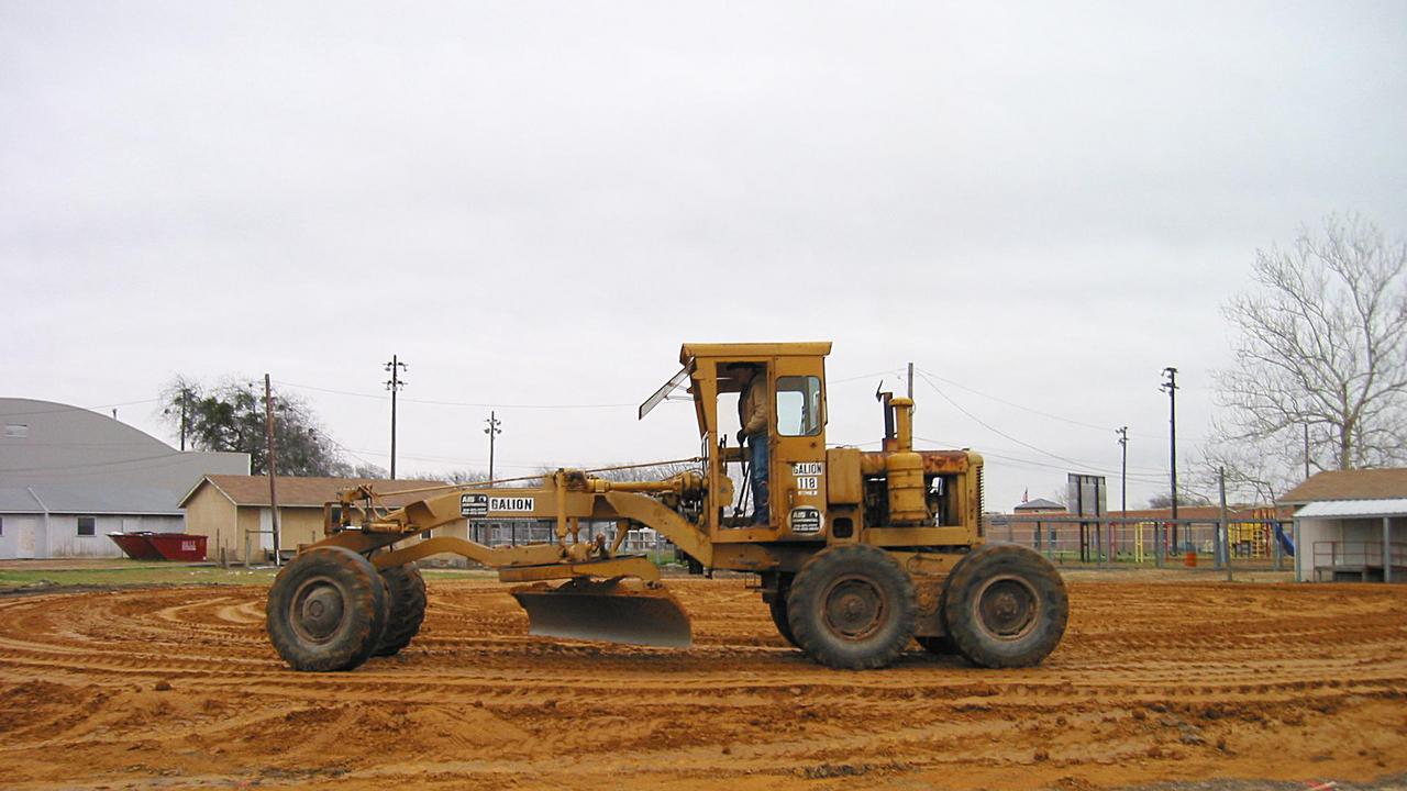 A road grader prepares the site for construction.