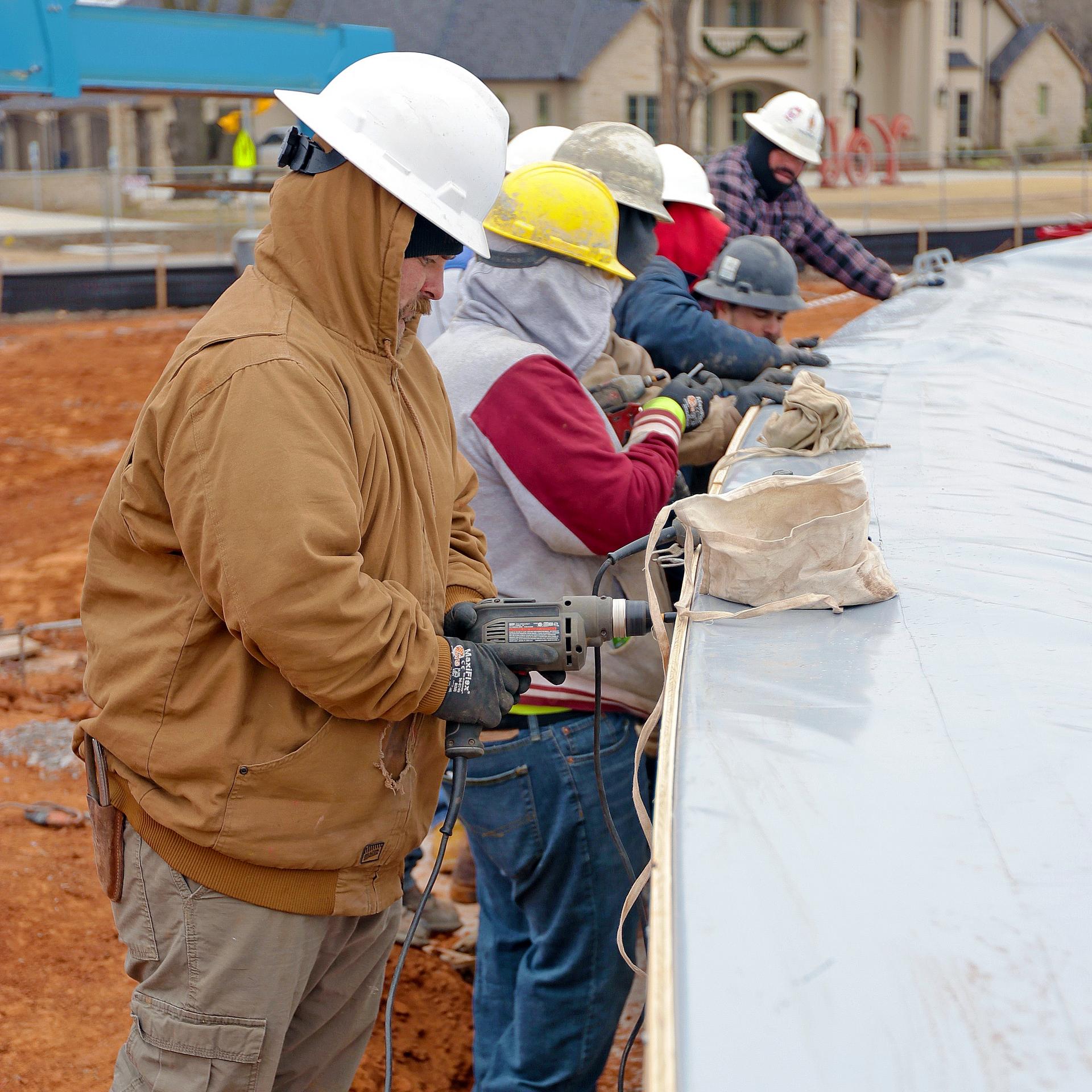 Workers attach the dome membrane to the outside edge of the tension ring.