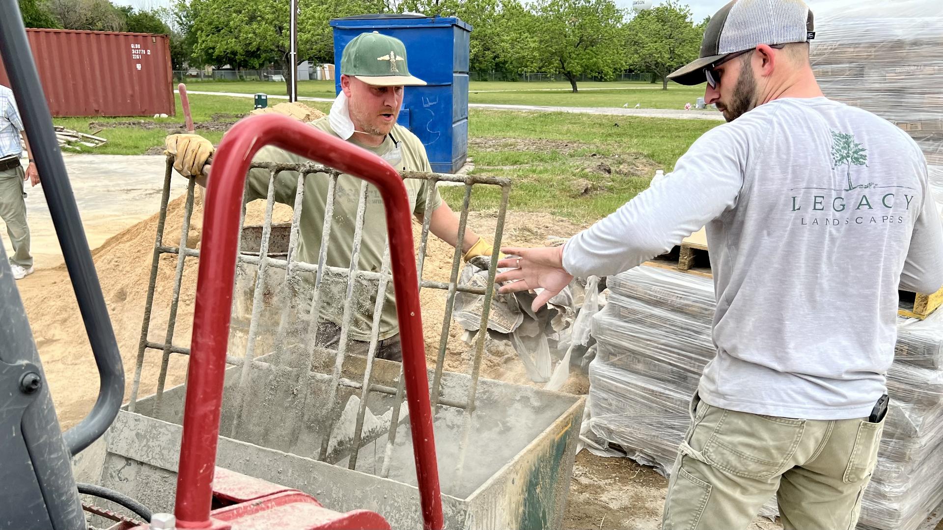 Two workshop students mixing concrete.
