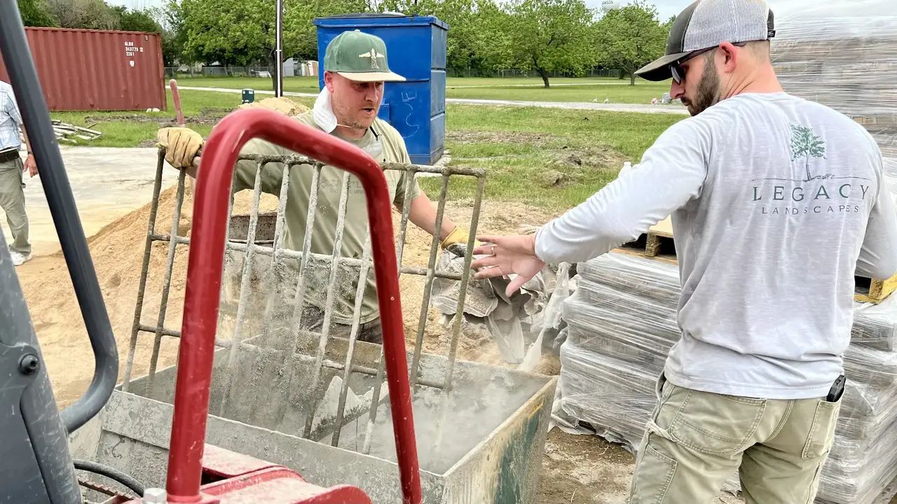 Two workshop students mixing concrete. Two workshop students mixing concrete.