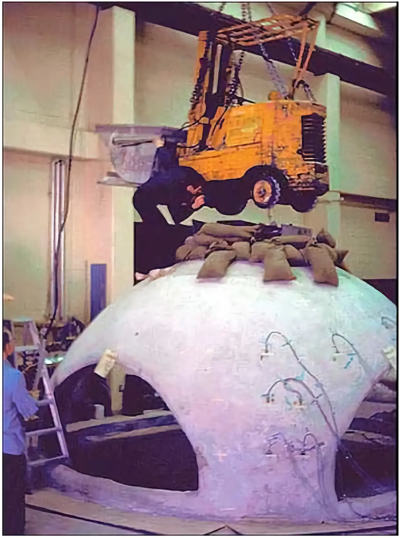 A forklift is lowered onto a concrete dome. A forklift is lowered onto a concrete dome.